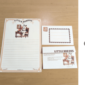 Little Bob Dog-themed stationery set: a white lined letter sheet with orange border and dog-at-desk illustration, plus a bordered note card and a matching business-card sized card.