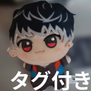Chibi plush figure with black-and-white hair and red eyes; white Japanese text 'タグ付き' overlays the bottom.