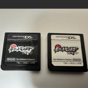 Two Nintendo DS game cartridges side by side: Pokémon Black (left) and Pokémon White (right). The black cartridge has a dark label, the white cartridge a light label with Pokémon branding.