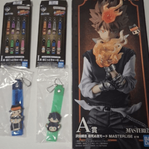Two chibi character keychains in plastic bags with metal clips, left blue strap and right green strap, plus a large Bandai figure box on the right featuring a fiery-haired character.