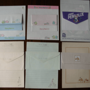 Assorted envelopes, notepads, and cards arranged on a wooden surface, featuring pastel colors and small illustrations throughout a grid layout.