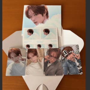 Set of idol photo cards arranged on a white display envelope on a wooden table.