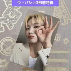 Promo photo of a person with blonde hair in a white blazer, making an OK sign near their face, with a purple banner of Japanese text above.