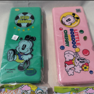 Two colorful Little Bobdog lunch boxes for kids: a green tin on the left with a running cartoon dog and logo, and a pink tin on the right with a cheerful pup and balloons.