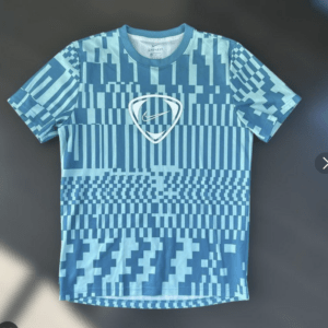 Blue athletic T-shirt with a digital geometric pattern and a white Nike swoosh inside a shield at the chest center.