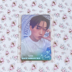 Glossy portrait photo card of a young man with dark hair, posed with hand near his cheek, on a blue-green gradient background with an emblem.