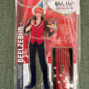 Cardboard cutout of a male anime character in a red vest and party hat, holding a birthday cake, packaged for sale on a red backdrop with accessories in plastic wrap.