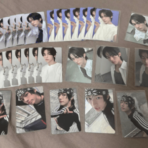 Collection of portrait and pose photocard cards featuring a young man in white outfits, laid out on a beige surface.