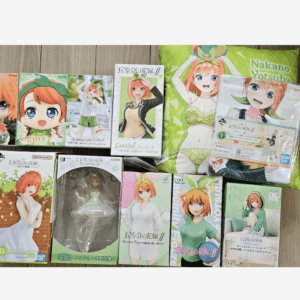 Collection of anime figure boxes featuring a red-haired girl in various poses and outfits arranged on a wooden floor, plus a green bag with the same character.