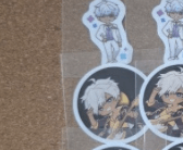 Sheet of circular stickers featuring a white-haired anime-style character, repeated across a corkboard or bulletin board.