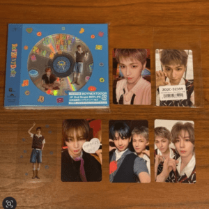 Blue Boy Next Door CD case with colorful decorations, plus several photo cards featuring male pop group members laid out on a wooden table.