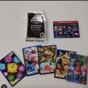 Collection of colorful Super Mario trading cards featuring characters like Koopa and friends, laid out on a light surface with a foil booster pack and an info insert nearby.