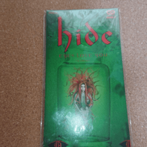 Green album cover for 'hide' featuring a glass jar with a figure inside and red stylized title at the top; the product is sealed in plastic.