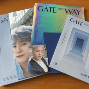 Multiple GATEWAY magazines with a rainbow-hued cover arranged on a wooden table, alongside a small photo card of a young man.