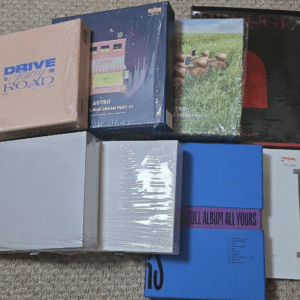 Collection of boxed vinyl records and sleeves laid on a beige carpet, with several album covers and spines partially visible.