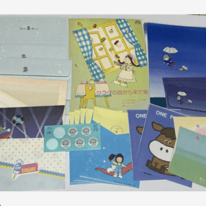 Collection of colorful children's stationery laid out on a table, including notebooks, envelopes, and cards with playful illustrations.