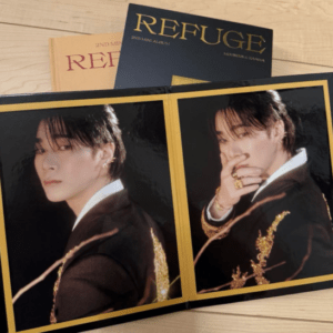 Open photo album with two portraits of a man in a black and gold embroidered jacket; Refuge magazines visible in the background.
