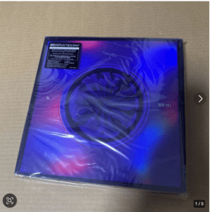 Holographic CD case on cardboard, gradient purple-blue cover with circular design and 'NEW DNA' text visible.