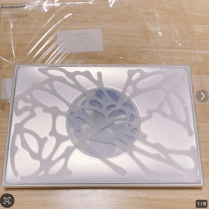 Decorative panel with white, coral-like branching pattern over a pale blue center, placed on a wooden surface.