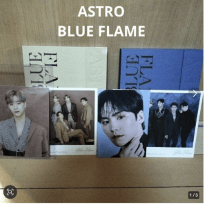 Display of ASTRO's Blue Flame album books with four member photocards laid in front.