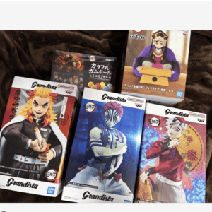 Collection of Grandista anime figure boxes laid on a brown blanket, featuring Demon Slayer characters such as Rengoku, Tanjiro, and Zenitsu.  Articulos Japan (Post Box Japan)
