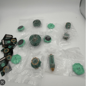 Green plastic model kit parts laid out on a white surface inside clear bags, with Bandai Namco cards on the left.  Articulos Japan (Post Box Japan)