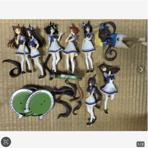 Collection of anime-style female figures in purple school uniforms laid out on a tatami mat, with extra hairpieces and green circular accessories nearby.