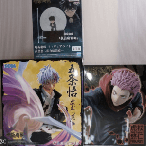 Three boxed anime figures arranged on a light striped background: a dark-haired figure box on top, with a display that resembles a snow globe; bottom left box features a blue-haired character with a swirling purple energy effect; bottom right box shows a pink-haired character in a dynamic pose.  Articulos Japan (Post Box Japan)