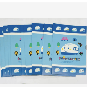 Stack of blue Shinkansen-themed notebooks with a smiling train illustration on the cover, arranged in a fan arrangement.