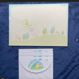 Pastel poster of a hilly landscape with trees and a rainbow slide on a blue fabric background.