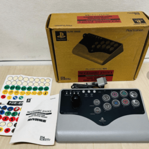 Programmable joystick with control pad and action buttons, box, instruction manual, and sticker sheet on a table surface.