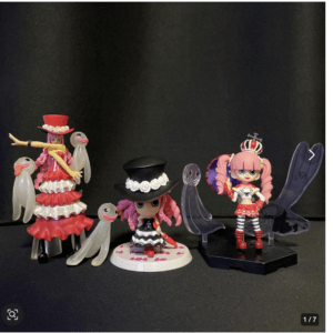 Group of colorful plastic fashion dolls with hats, wings, and accessories arranged on a dark surface.