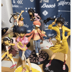 Collection of colorful anime character figurines arranged on a wooden desk in front of a blue poster backdrop.