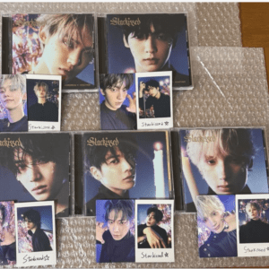 A collection of CD cases and Polaroid-style photo cards featuring group members, laid out on bubble wrap.