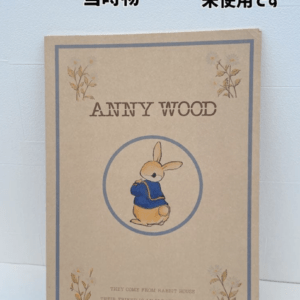 未使用のレトロなファンシーノート。表紙にウサギが青い服を着て座るイラストと Annie Wood の文字。花柄の枠も添えられている。