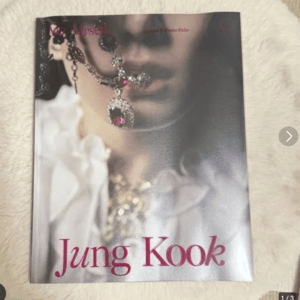 Close-up of a jewelry necklace on a magazine cover, with pink 'Jung Kook' text at the bottom edge.
