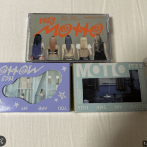 Three ITZY Motto album boxes arranged on a light surface, showing colorful covers with the band members from the back on the top box and pastel designs on the bottom left and right boxes