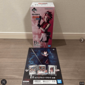 Boxed anime figure set on a wooden floor, with pink Bandai Namco packaging in the background and a poster showing a ninja with blue lightning in front.