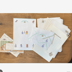 Collection of pastel stationery and envelopes with cartoon characters on a wooden table, including sheets and folders for kids' correspondence.