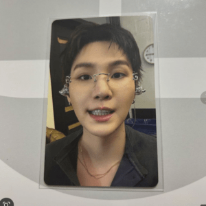 Close-up photo of a person with braces wearing decorative, wire-framed glasses in a framed portrait display on a grey wall.