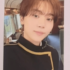 Young man with light brown hair wearing a black uniform with gold trim, taking a selfie inside a vehicle or train carriage.