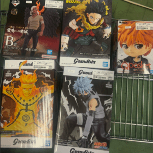 Five Grandista boxed anime figures on a metal shelf, including Naruto and Ichigo, displayed in a store.