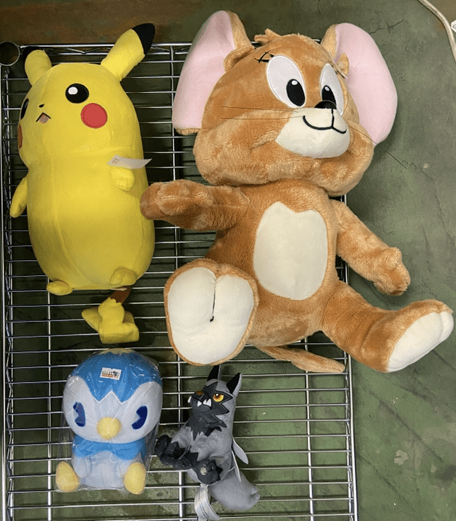 Captura De Pantalla 2026-07-02 a Las 184439 - Articulos Japan (post Box Japan) Four stuffed animals on a metal rack: a large yellow Pikachu-like plush, a brown bunny, a blue penguin, and a small gray wolf. Articulos Japan (Post Box Japan)