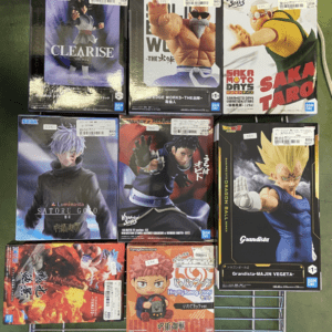 Boxed anime figures on a metal display rack, featuring characters like Satoru Gojo and Dragon Ball Z figures in their packaging.