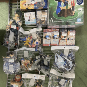 Whole rack of anime figures and boxes arranged on a metal display shelf, assorted character figurines in plastic bags and their packaging visible.