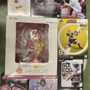 Shelf of anime figure boxes on a metal rack; center shows an Overlord figure, surrounded by other boxed characters with colorful artwork (pink-haired figure left, yellow character right).