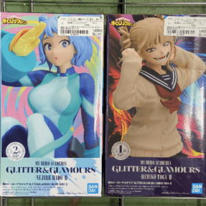 Two boxed My Hero Academia Glitter & Glamours figures on a wire rack: left a blue-haired heroine in a teal suit, right a tan-haired student in a sailor-style outfit with scarf.