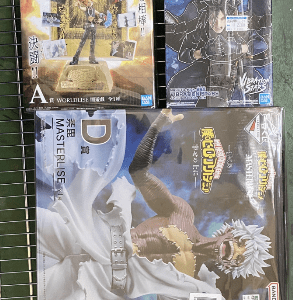 Three boxed anime action figures on a wire display rack, with colorful cover art and Japanese text.
