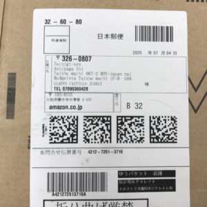 Shipping label on a cardboard box with Japanese address, barcode, and QR codes, including an amazon.co.jp line.