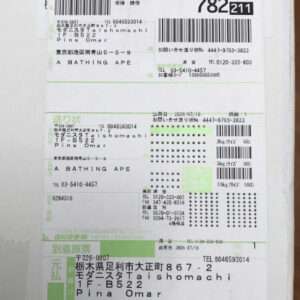 Close-up of a Japanese shipment label with several barcodes, tracking numbers, and sender/recipient text; green section borders separate shipping details.